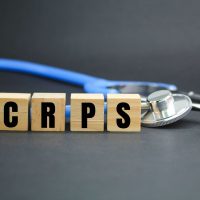 stethoscope and wooden cube with the letters CRPS or the word complex regional pain syndrome